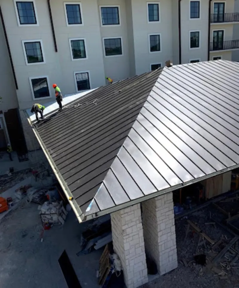 Crew installing standing seam metal roof panels on a commercial project in Taft
